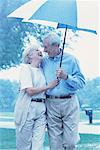 Mature Couple Walking Under Umbrella in Rain