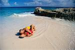 Couple d'âge mûr en maillot de bain, couché sur la plage, baiser