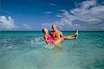 Mature Couple in Swimwear, Man Carrying Woman in Water