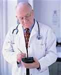Mature Male Doctor Using Electronic Organizer