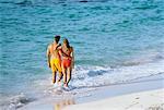 Vue arrière du Couple en maillot de bain marcher sur la plage