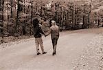 Vue arrière du famille marchant sur une route de campagne en automne