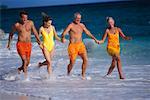 Two Couples in Swimwear, Running In Surf on Beach, Holding Hands