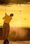 Rückansicht des Mannes schlagen Golfball aus Sand Trap