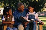 Vater Lesung zu Töchtern sitzen auf der Parkbank