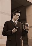 Businessman Holding Cell Phone And Pager Outdoors