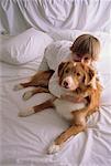 Portrait of Boy with Dog on White Bed