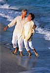 Mature Couple Walking in Surf on Beach