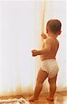 Child in Diapers Looking Out of Window