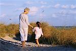 Back View of Grandmother and Granddaughter Walking on Beach Holding Hands