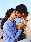 Couple Holding Drinks and Kissing On Beach