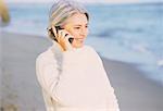 Mature femme sur la plage à l'aide de téléphone portable