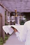 Waiter Carrying Bottle of Wine And Glasses on Tray