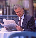 Mature Businessman Reading Newspaper at Outdoor Cafe