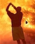 Silhouette d'homme jouer au golf au lever du soleil