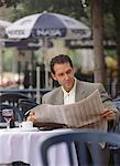Homme d'affaires de lecture de journal au café en plein air