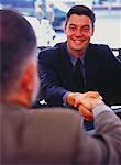 Businessmen Shaking Hands at Table in Restaurant