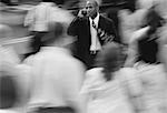 Businessman Using Cell Phone on Busy Street