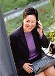 Businesswoman Using Cell Phone And Laptop Computer Outdoors