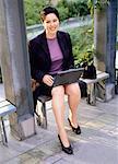 Portrait de femme d'affaires assis sur un banc avec ordinateur portable