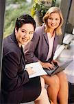 Businesswomen Sitting on Park Bench with Laptop and Agenda