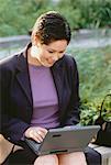 Femme d'affaires assis sur un banc à l'extérieur à l'aide d'ordinateur portable