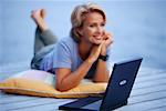 Portrait of Mature Woman Lying on Dock with Laptop Computer