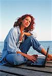 Woman Sitting on Dock Using Laptop Computer