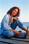 Portrait de femme assise sur le quai à l'aide d'ordinateur portable