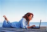 Femme allongée sur le quai à l'aide d'ordinateur portable