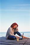 Woman Sitting on Dock Using Laptop Computer