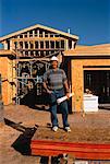 Man with Blue Prints Standing in Front of House Under Construction