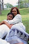 Portrait of Mother and Daughter Sitting on Grass Embracing
