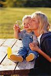 Mother and Son Sitting on Picnic Table Blowing Bubbles