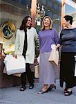 Three Women Walking on Street Carrying Shopping Bags