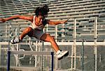 Woman Jumping over Hurdles in Stadium