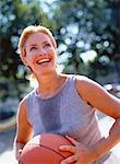 Mature Woman Holding Basketball Perspiring Outdoors and Smiling