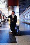 Businessman Leaning on Pillar Using Cell Phone in Terminal