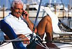 Mature Man Sitting in Boat, Using Cell Phone