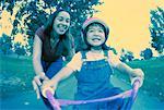 Mother Helping Daughter Learn to Ride Bicycle in Park