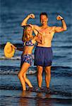 Portrait of Couple in Swimwear Flexing Muscles on Beach Ontario, Canada