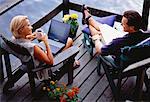 Mature Couple Sitting in Adirondack Chairs on Deck with Laptop Computer