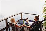 Mature Couple Sitting in Adirondack Chairs on Deck with Laptop Computer