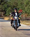 Mature Man Riding Motorcycle Carrying Bouquet of Flowers