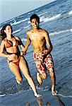 Teenage Couple in Swimwear Running on Beach