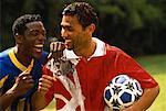 Zwei männliche Fußball-Spieler, bedeckt im Schlamm, lachen