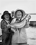 Portrait de deux hommes matures tenant les grands et les petits poissons