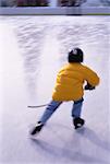 Back View of Boy Playing Hockey At Outdoor Ice Rink