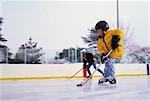 Vater und Sohn an im freien Eisbahn Hockey spielen