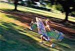 Boy Running with Cardboard Airplane Outdoors